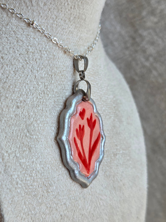 Medalla rosada y rojo con pátina plateada y cadena con baño de plata