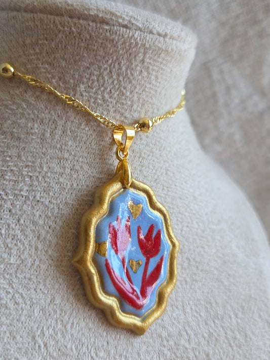 Medalla celeste y rojo con pátina dorada, detalles en oro y cadena con baño de oro