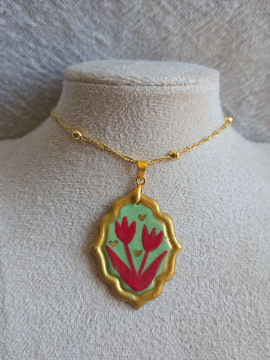 Medalla verde y rojo con pátina dorada, detalles en oro y cadena con baño de oro