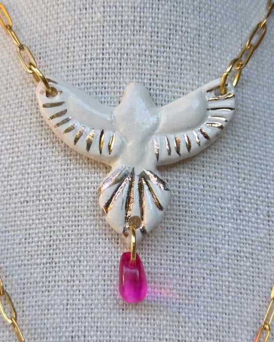 Collar pájaro blanco y lustre de oro con lagrimita fucsia y cadena con baño de oro