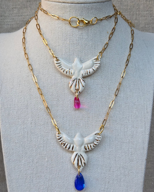 Collar pájaro blanco y lustre de oro con lagrimita fucsia y cadena con baño de oro