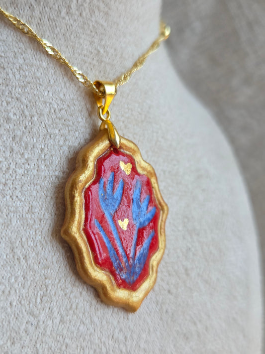 Medalla rojo y azul marino con pátina dorada, detalles en oro y cadena con baño de oro