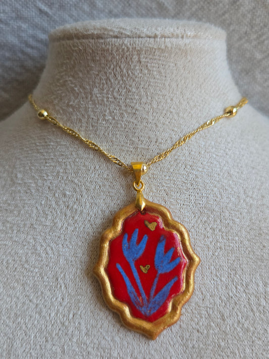 Medalla rojo y azul marino con pátina dorada, detalles en oro y cadena con baño de oro