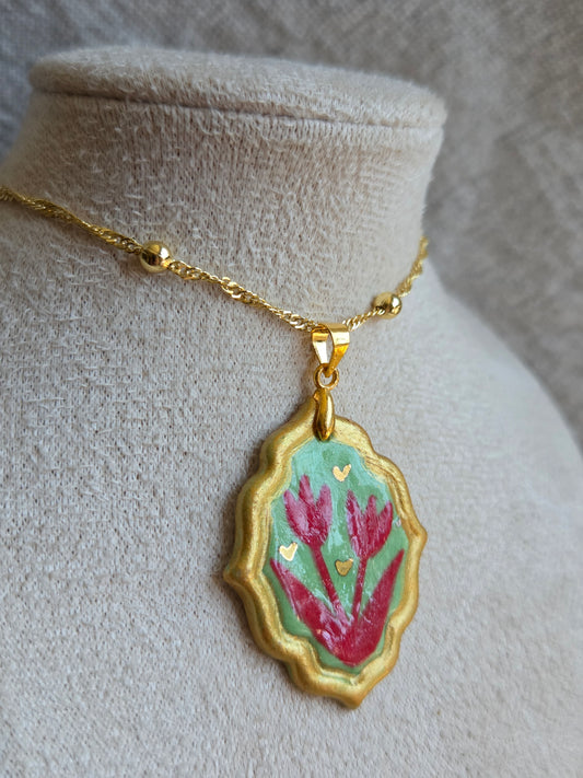 Medalla verde y rojo con pátina dorada, detalles en oro y cadena con baño de oro